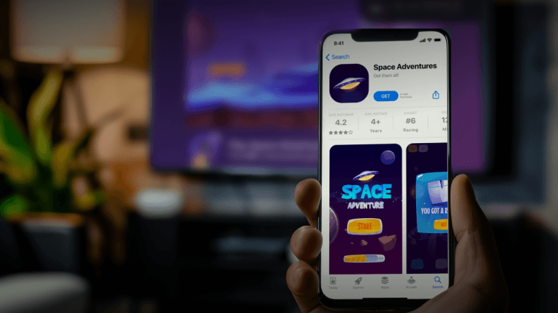 Hand holds a smart phone that shows an app called Space Adventures available in app tore on the device