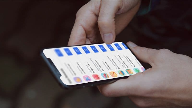 Person holding a mobile device showing a list of apps with blue call to action-buttons