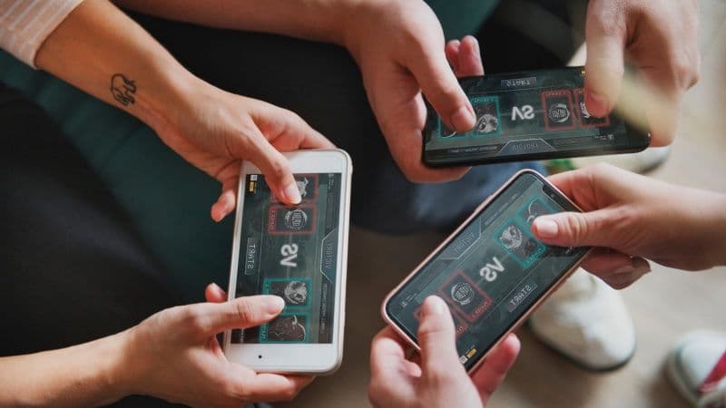 three persons using their mobile devices horizontally playing a game