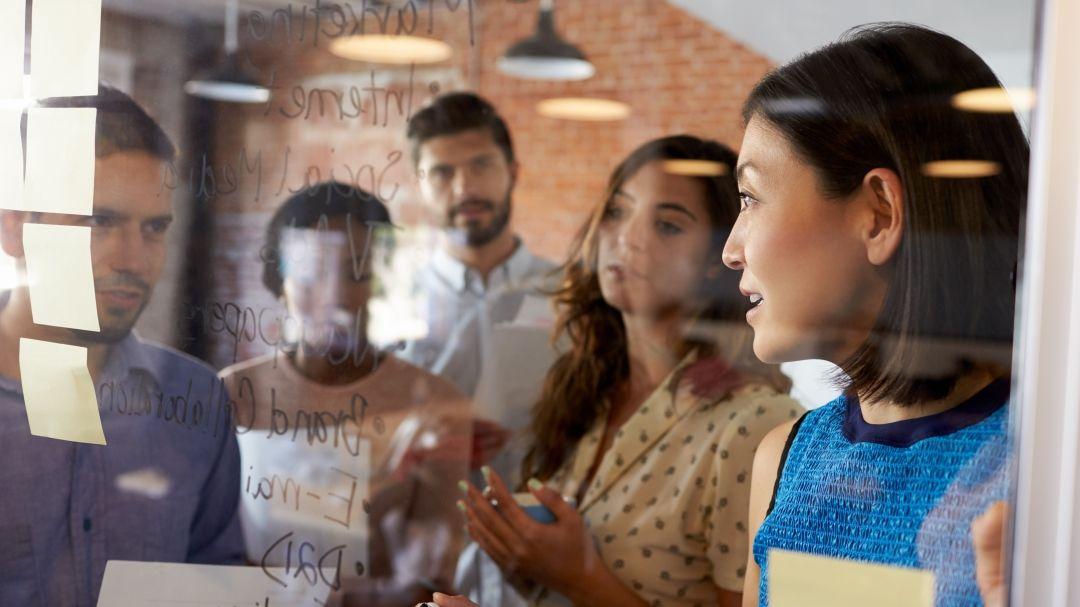 A group of people standing in front of a board with sticky notes.