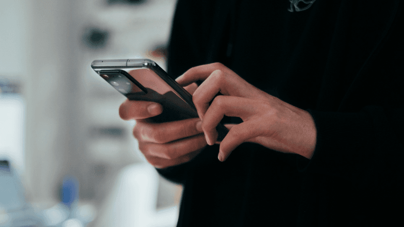 Mãos digitando na tela do telefone