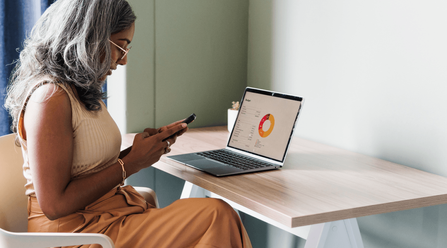 Person sitting at a desk looking at their mobile phone
