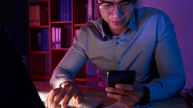 Homme utilisant un téléphone et un ordinateur portable