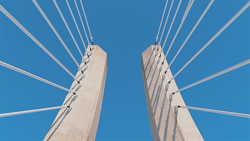 Cables on a bridge viewed underneath against a clear blue sky