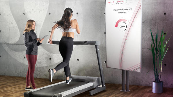 Person running on a treadmill with an evaluator to the side