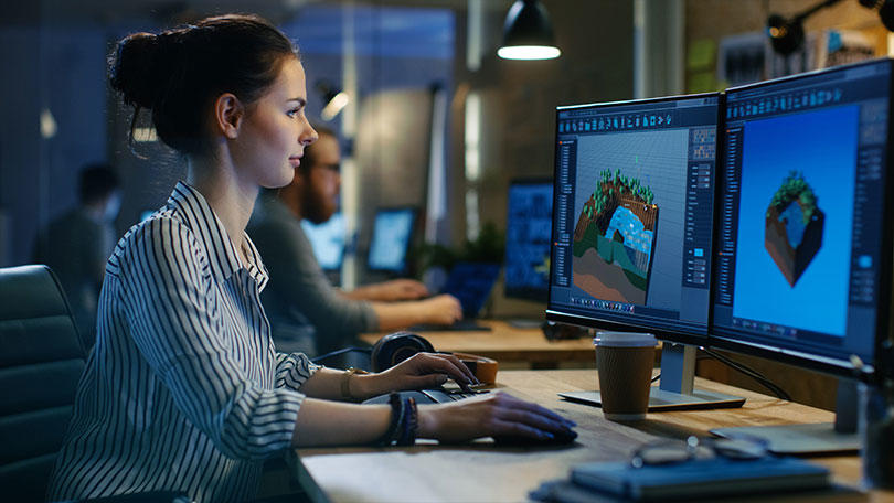 オフィスのコンピューターを操作しているゲーム開発者の女性