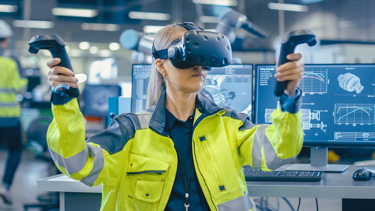 Woman with a VR headset and controllers in an industrial workspace